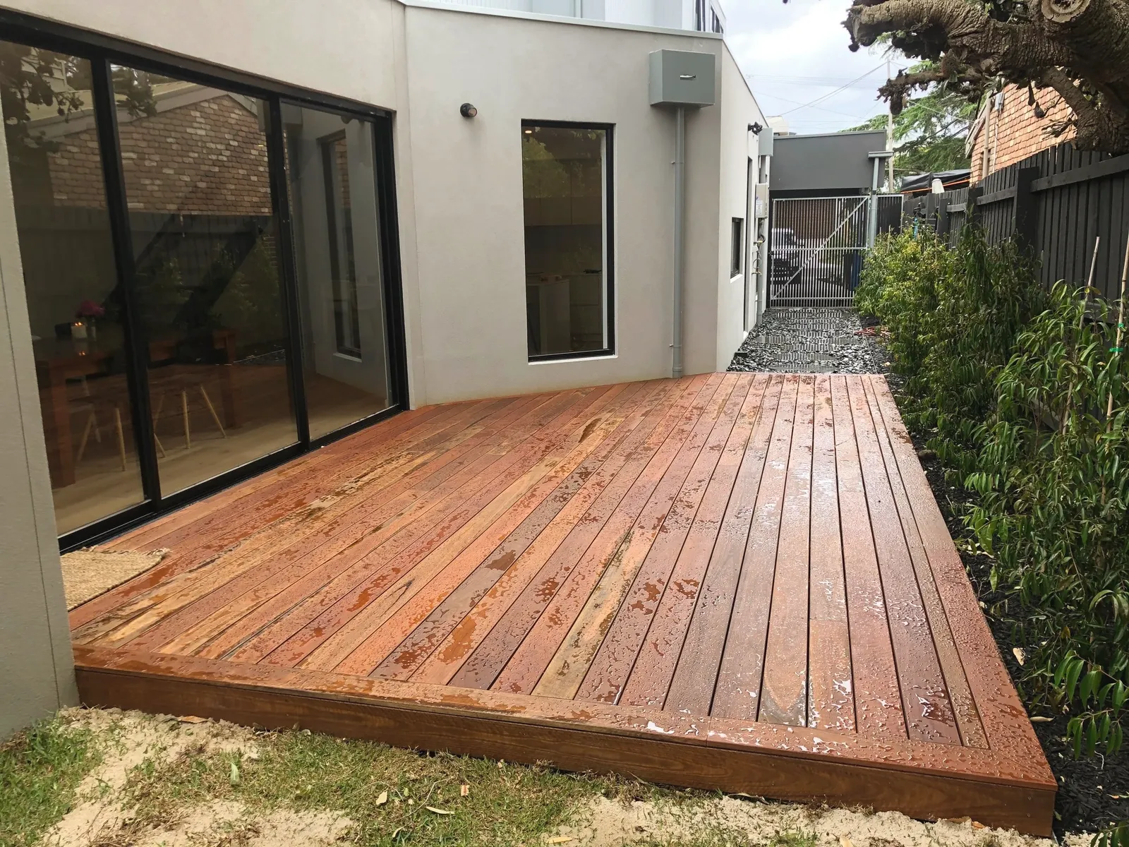 Merbau timber deck built off the back of a rendered house, sitting level with the interior floor