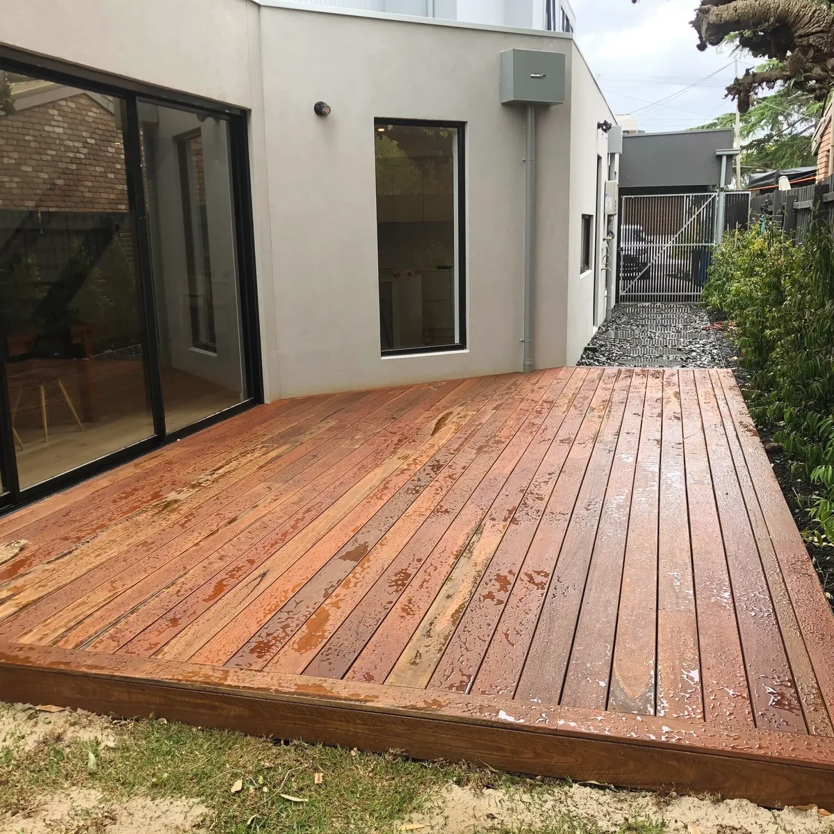 Merbau timber deck built off the back of a rendered house, sitting level with the interior floor